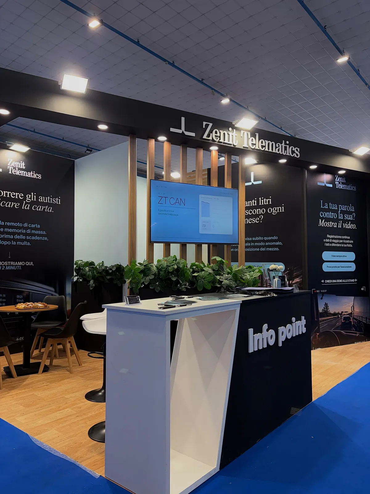 The Zenit Telematics stand at a trade fair: info point in the foreground, a screen showing ZT CAN and panels on tachograph, fuel consumption and dashcam