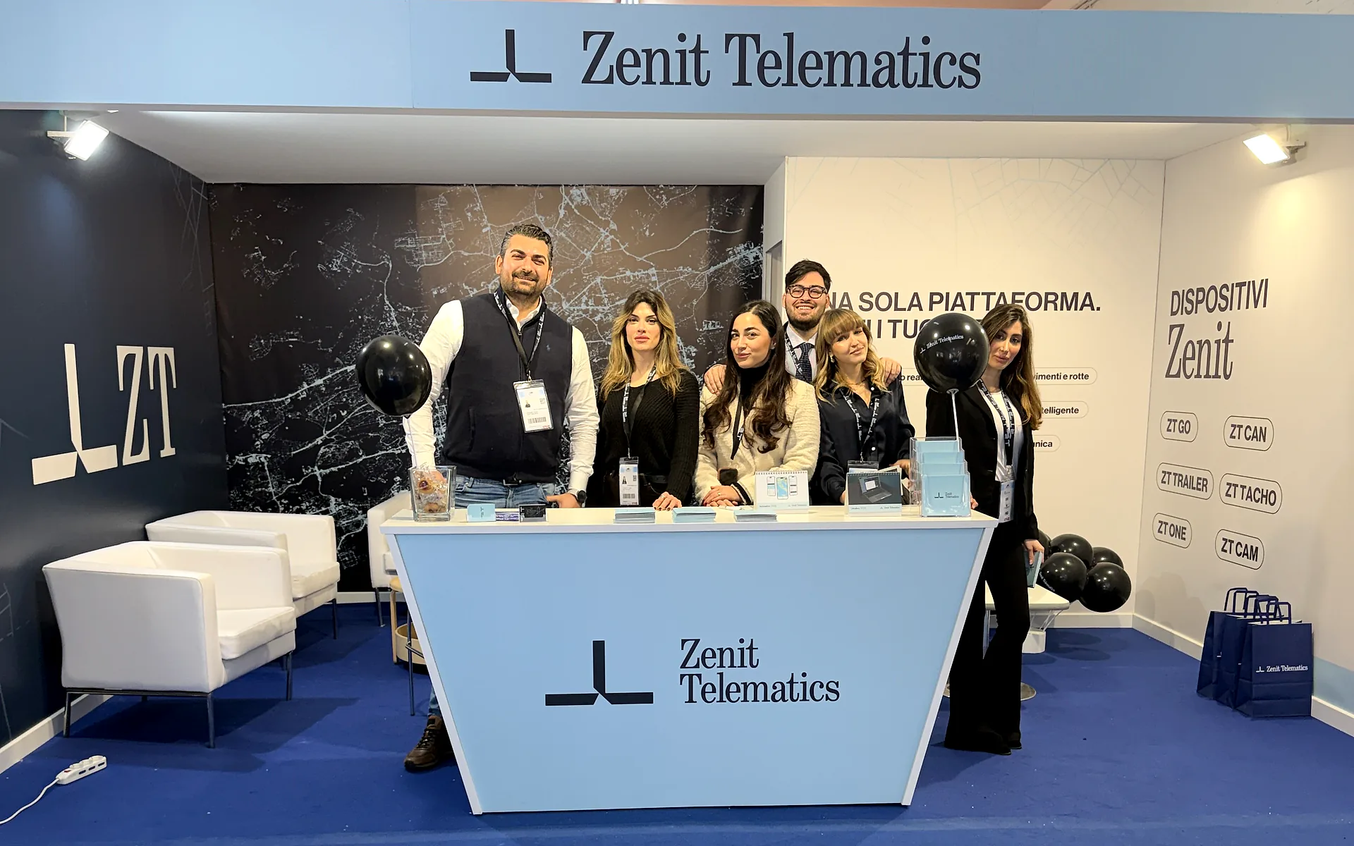 The Zenit Telematics team of six behind the stand counter at Nauticsud 2026, with the Zenit devices panel on the right