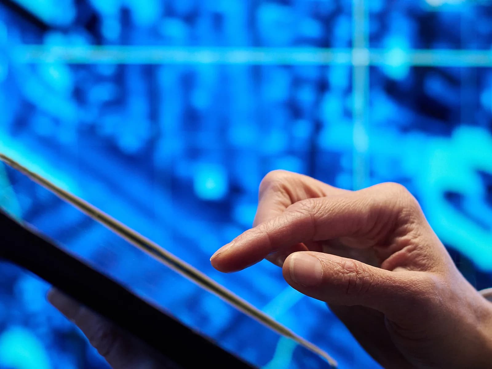 Mano che interagisce con un tablet in un ambiente tecnologico